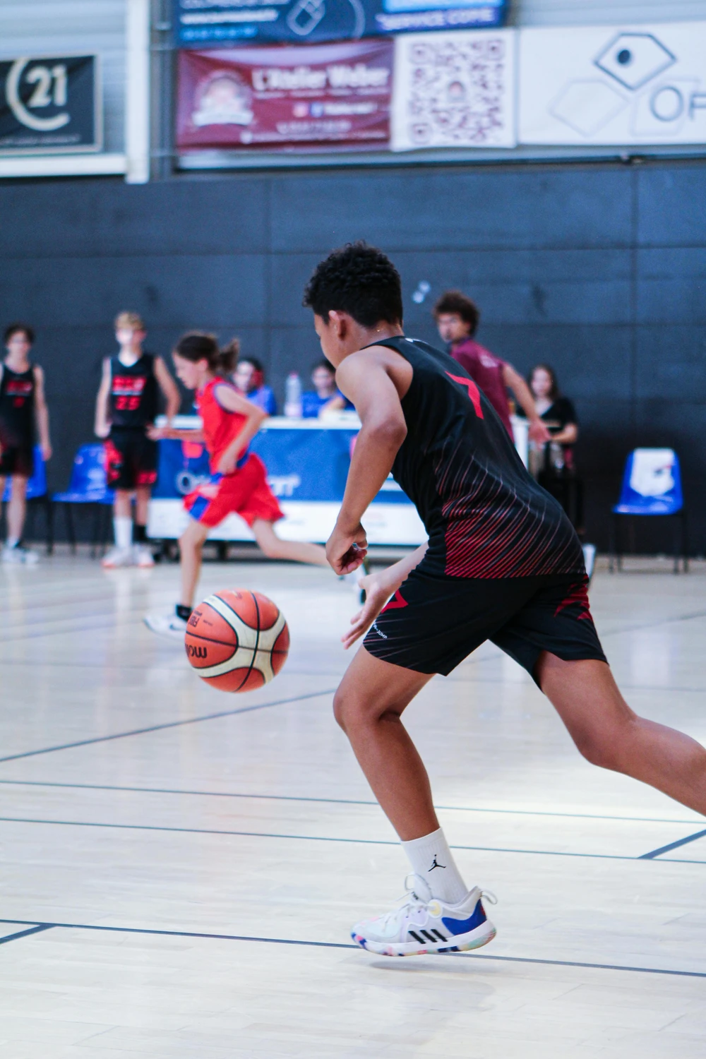 Several students are playing basketball in the school gymnasium.