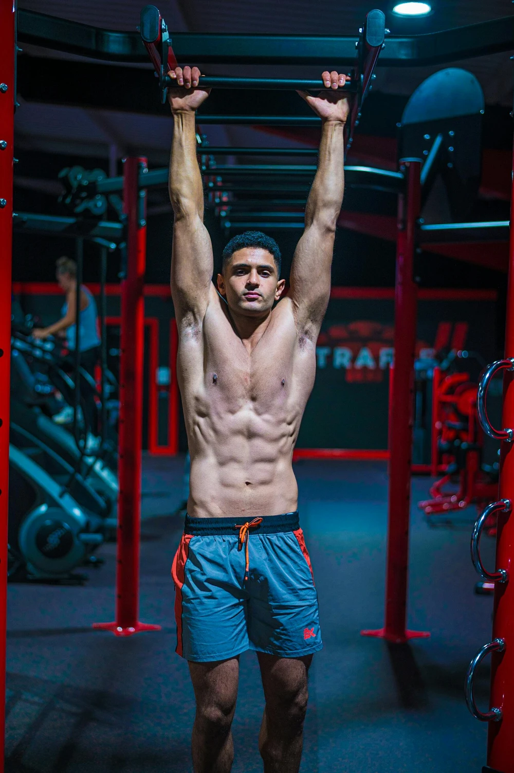A young man is doing pull-ups on a power rack.
